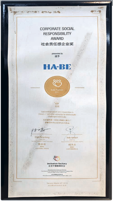 Eine gerahmte Urkunde über den Corporate Social Responsibility Award, die HA-BE verliehen wurde, mit englischem und chinesischem Text, einem goldenen runden Emblem und Unterschriften am unteren Rand.