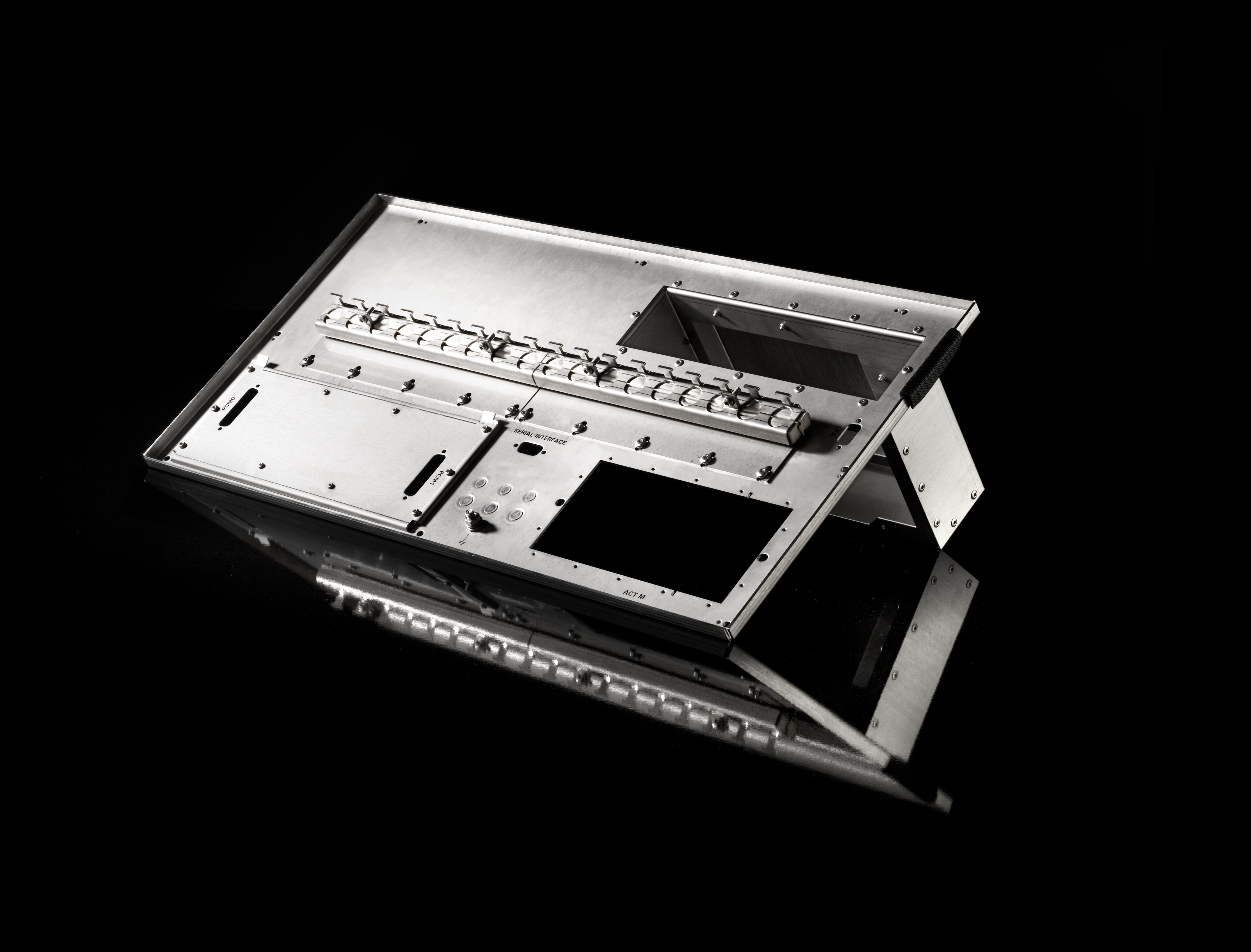 Ein rechteckiges Metallgehäuse mit mehreren Ausschnitten und Befestigungslöchern, das auf einer reflektierenden schwarzen Oberfläche ruht. Die Struktur scheint ein Bauteil für elektronische oder mechanische Geräte zu sein.